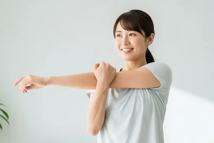 笑顔で肩のストレッチをする女性